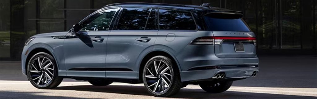 A grey 2025 Lincoln Aviator parked next to a city building near downtown Elizabethtown, KY, in the daylight.
