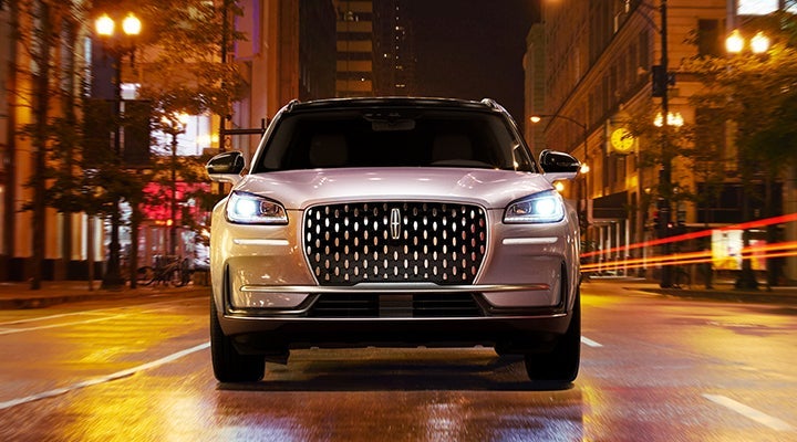 A 2024 Lincoln Corsair driving through downtown Elizabethtown, KY, at night, illuminated by beams of light. The warm glow of streetlights enhances the evening atmosphere.