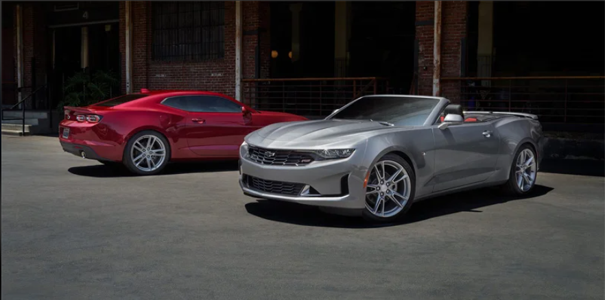 A red 2024 Chevrolet Camaro and a silver Chevrolet Camaro parked outside near Commonwealth Chevrolet.