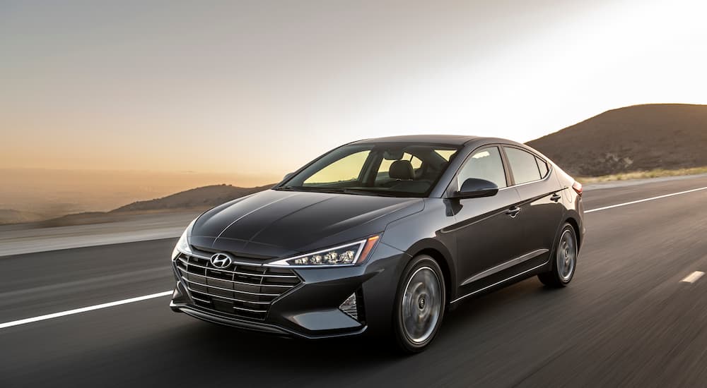 A grey 2020 Hyundai Elantra SE driving on a road at dusk.
