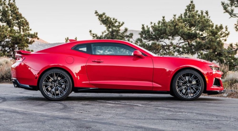 Side view of a red 2017 Chevy Camaro ZL1 parked on a mountain overlook.