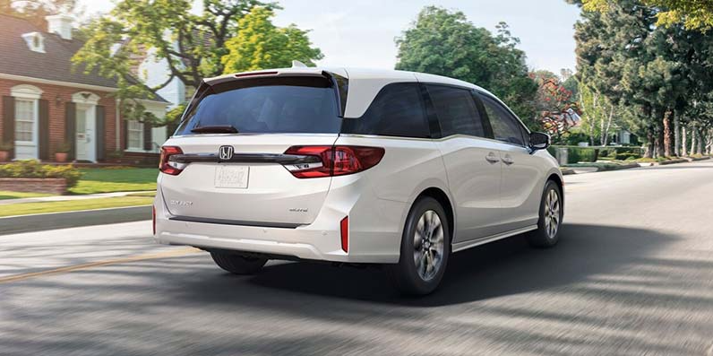 A white 2026 Honda Odyssey driving down the road.