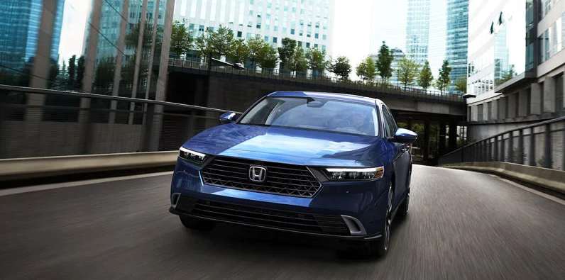 A photo of a blue 2025 Honda Accord driving down a city street. 