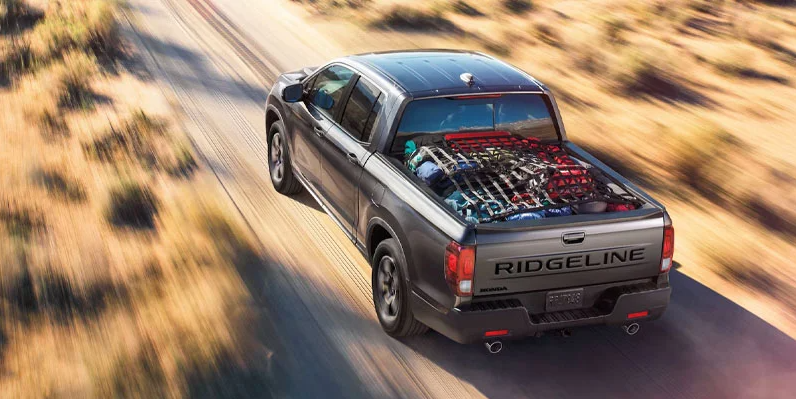 A dark grey 2024 Honda Ridgeline driving down a dirt road near Coeur d'Alene Honda.