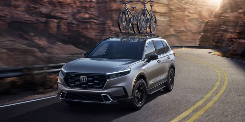A 2025 Honda CR-V driving down the road with 2 bikes on the roof rack.