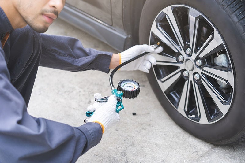 ford technician checking the air pressure of a vehicles tire at the shop