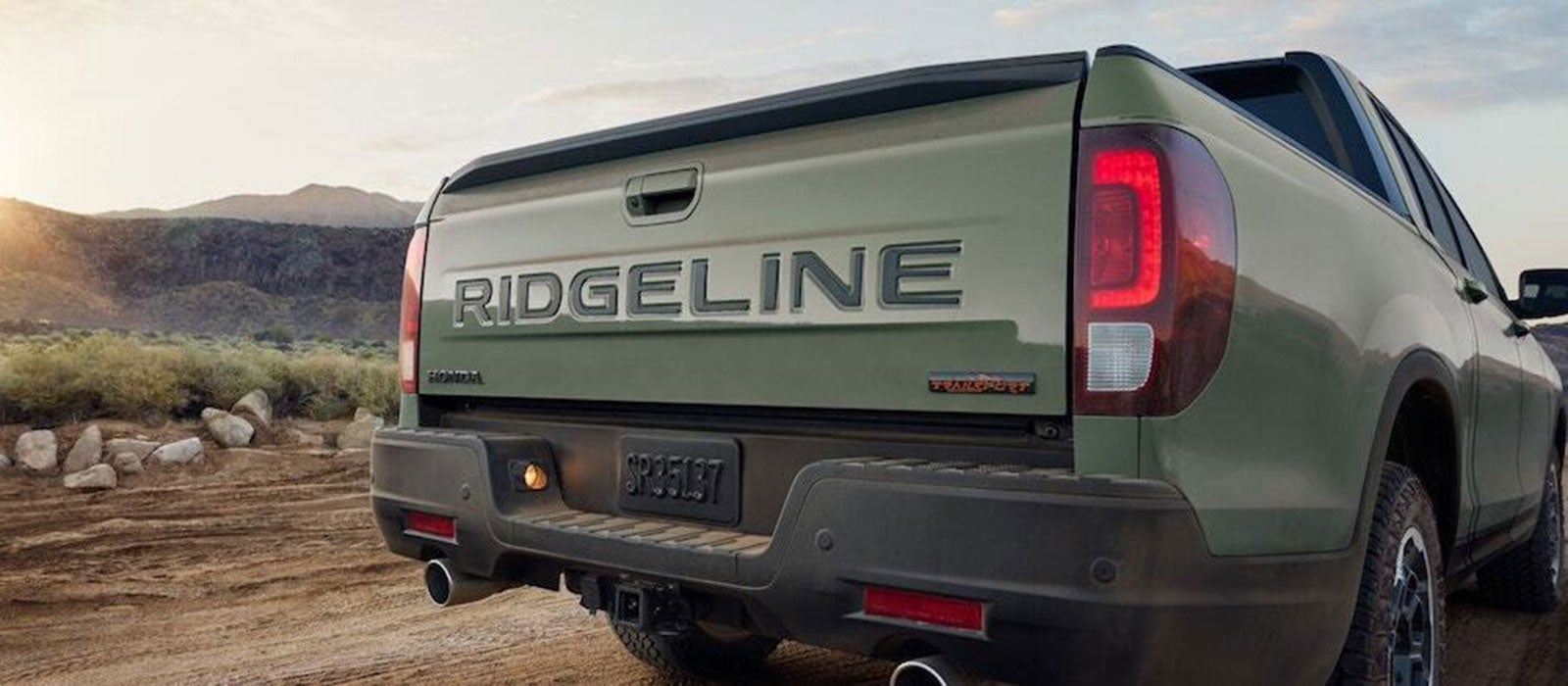 A view of the tailgate of a light green 2026 Honda Ridgeline, featuring the Ridgeline name in black lettering
