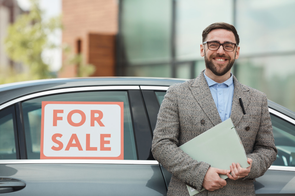 Salesman in front of a car that is for sale. 
