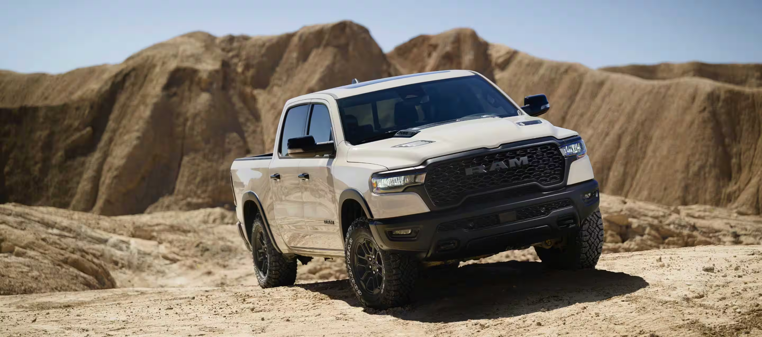 2025 RAM 1500 Rebel X driving outside on a dirt road near a cliff