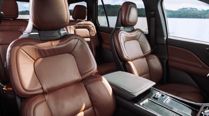 Interior view of a 2024 Lincoln Aviator featuring reddish-brown leather seats, showing the driver, passenger, and back row seating.