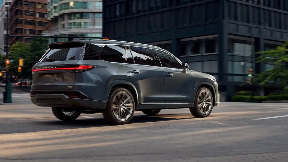 A gray 2026 Lexus TX SUV rounding a corner on a city street
