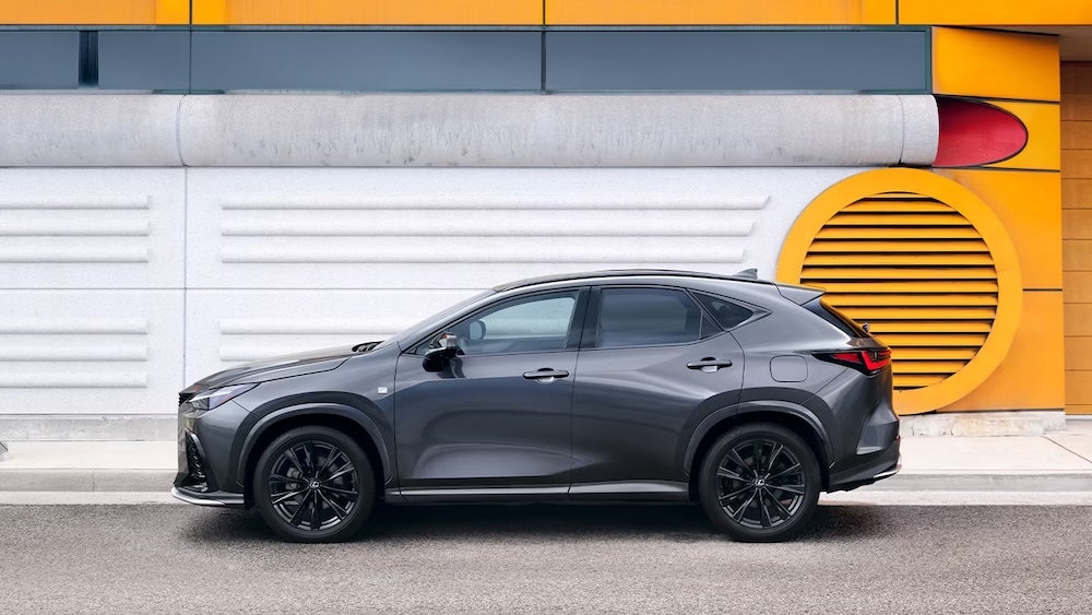 A side view of a gray 2026 Lexus NX SUV parked in front of a white and yellow wall
