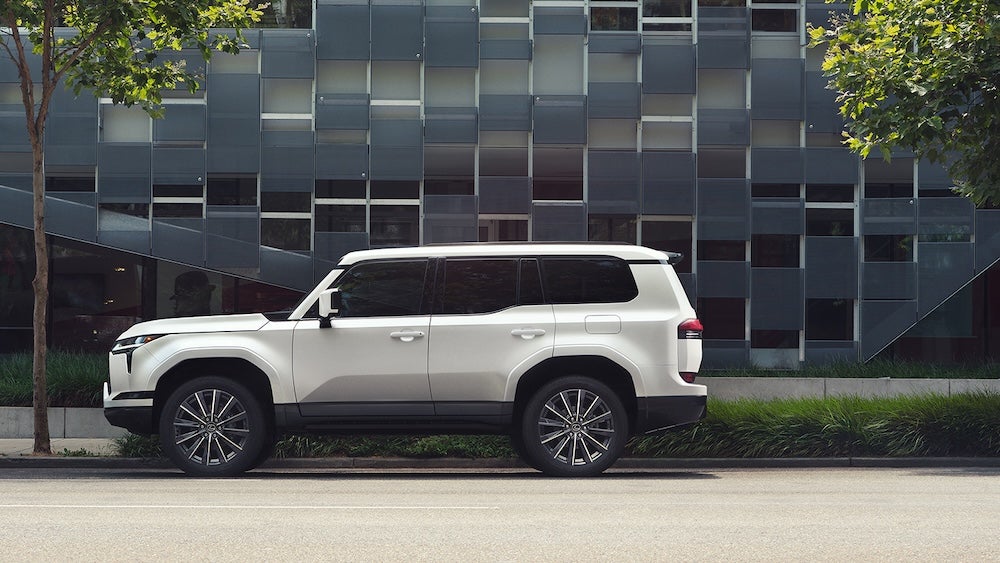 A side view of a white 2026 Lexus GX SUV parked beside a building