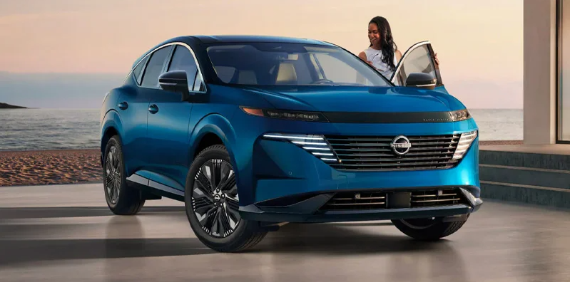 A woman climbing in to the drivers side of a blue 2025 Nissan Murano.
