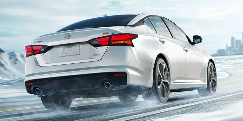 A photo from the rear of a 2025 Nissan Altima driving through a snowy road.
