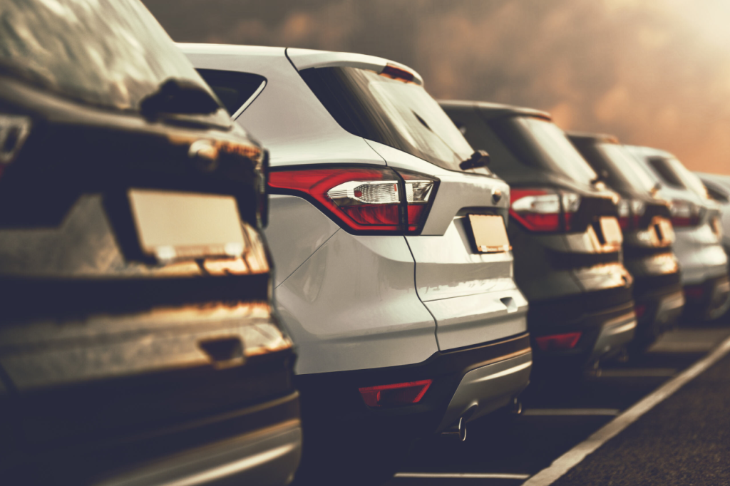 picture of several cars lined up in a car dealerships parking lot.