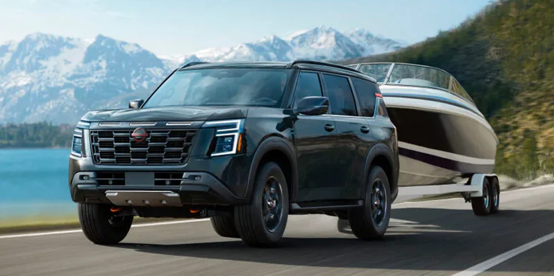 A 2025 Nissan Armada towing a boat down the road.