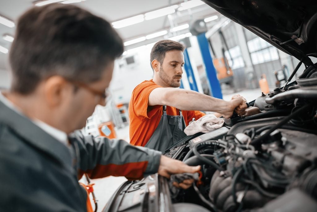 Mechanics inspecting a vehicle engine during an automotive service repair.
