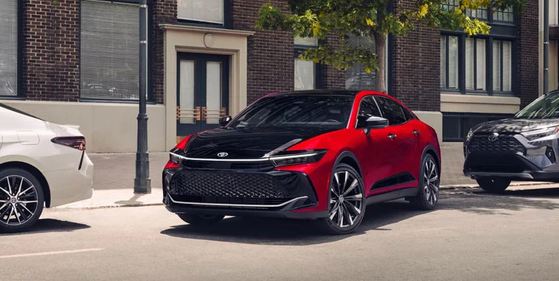 A red and black Toyota Crown parallel parking on a city street.