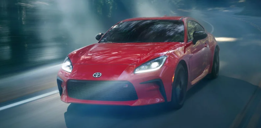 A 2024 Toyota GR86 driving down the road near Woodrum Toyota of Macomb.