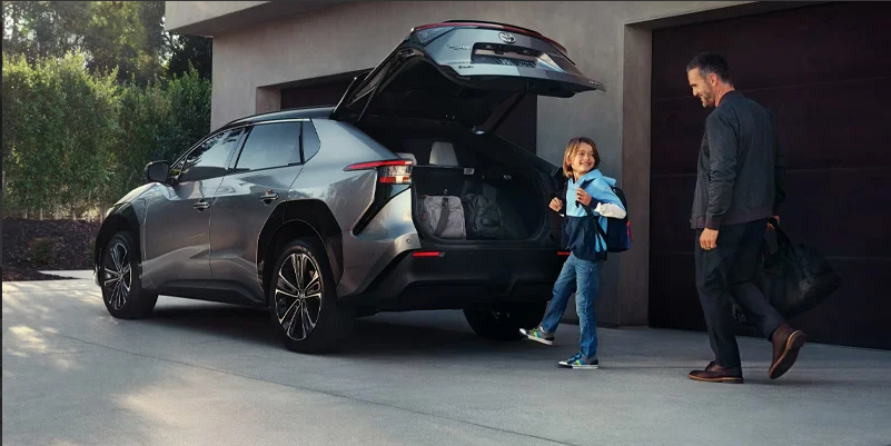 A man and his soon walking toward the rear of a 2025 Toyota bZ4X.