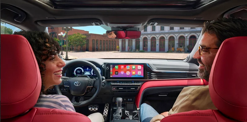 Two individuals sitting in the front seats of a 2025 Toyota Camry.