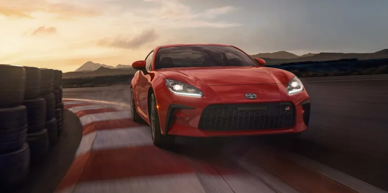 A red 2025 Toyota GR86 rounding the corner on a race track.