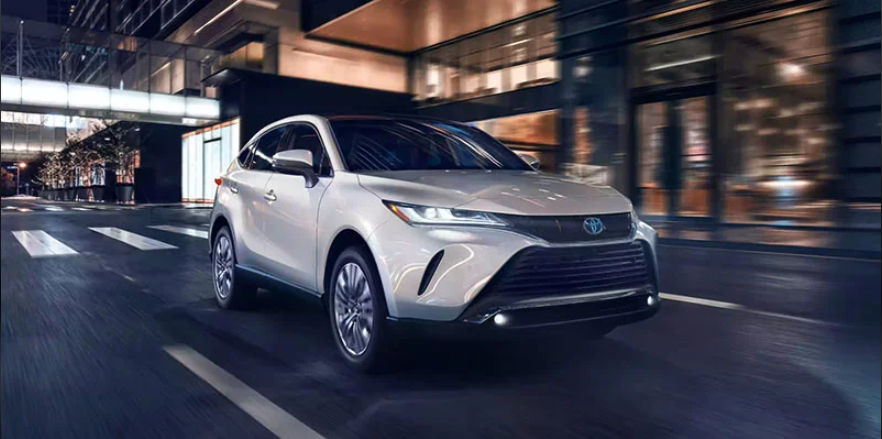 A Silver 2024 Toyota Venza driving down the road at night near Woodrum Toyota of Macomb.