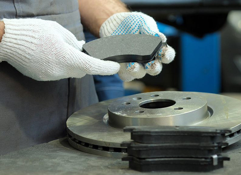 A close up of someone working on a cars brakes.