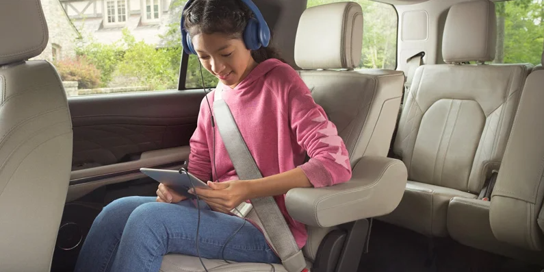 A young girl sitting in the backseat of a 2024 Ford Expedition Max listening to something with her headphones.