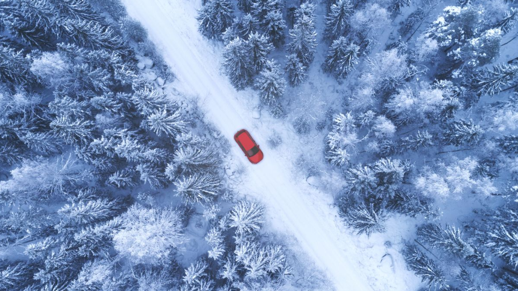A birds eye view photo of a road through a wooded area covered in snow.