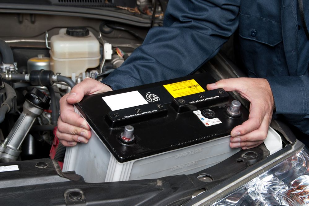 A person changing the battery on a car.