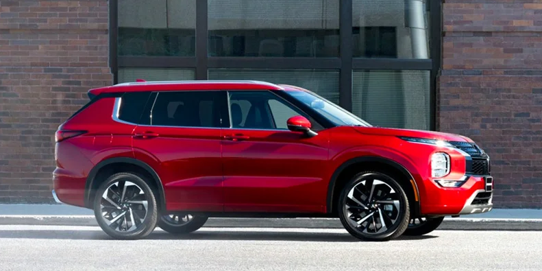 A red 2024 Mitsubishi Outlander parked on the side of the road.