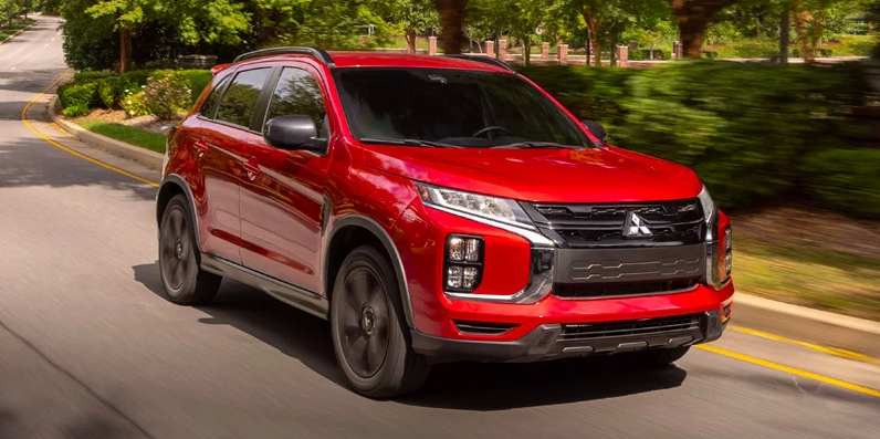 A red 2025 Mitsubishi Outlander driving down the road.