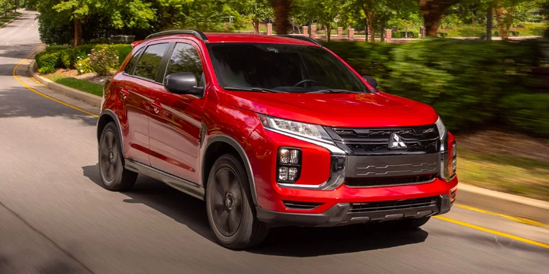 A red 2025 Mitsubishi Outlander sport driving down the road.