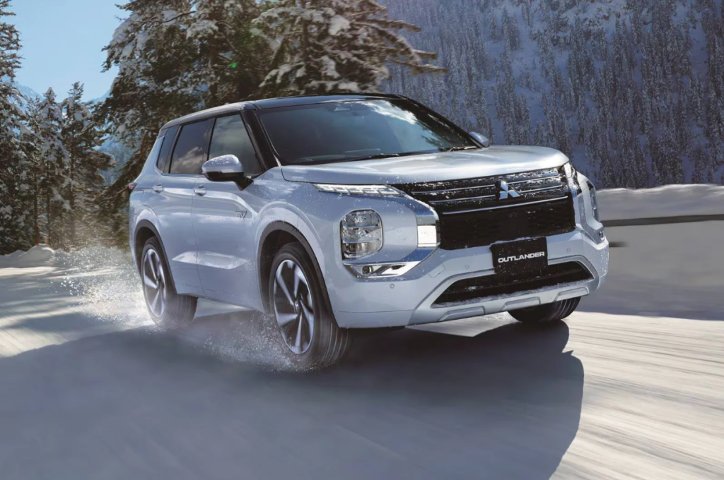 A 2025 Mitsubishi Outlander PHEV driving down a snow filled road.
