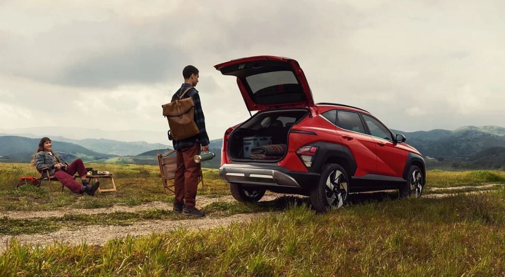 People are shown relaxing near a red 2024 Hyundai Kona Limited.