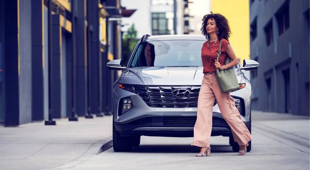 A woman walking by a parked grey 2024 Hyundai Tucson.