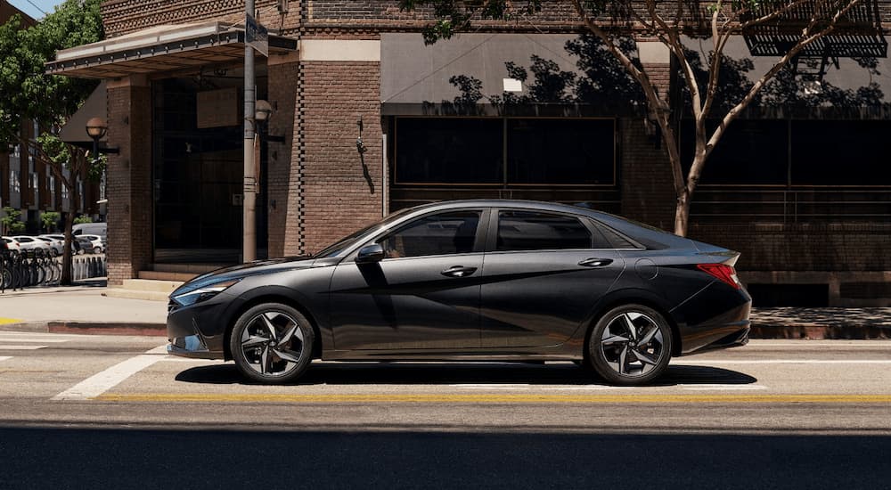Side angle view of a black 2021 Hyundai Elantra stopped by a building.