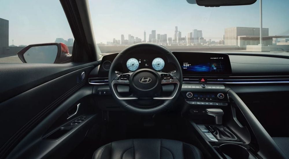 The black interior of a 2024 Hyundai Elantra is shown from the driver's seat.
