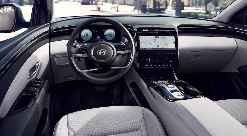 the white and black interior of a 2022 Hyundai Tucson is shown from the driver's seat.