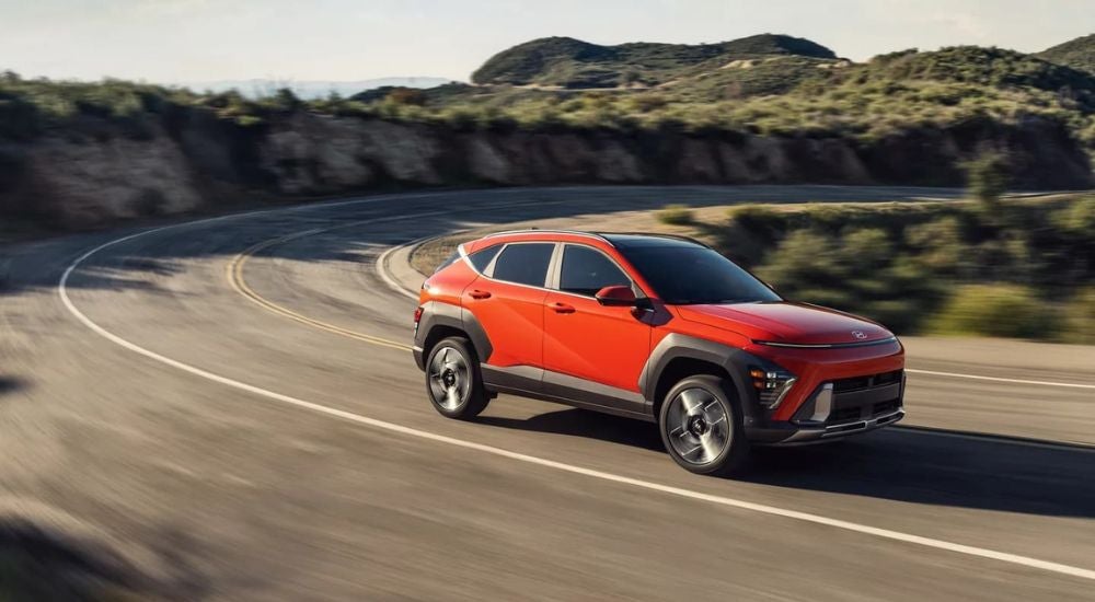 A red 2024 Hyundai Kona Limited is shown driving to a Hyundai dealer in Seekonk.