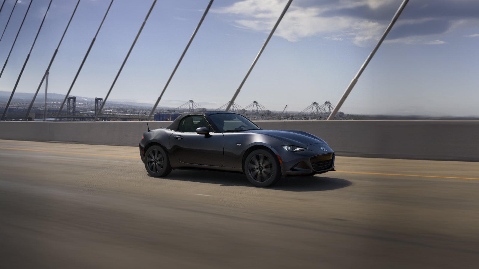 grey mazda miata driving on the road
