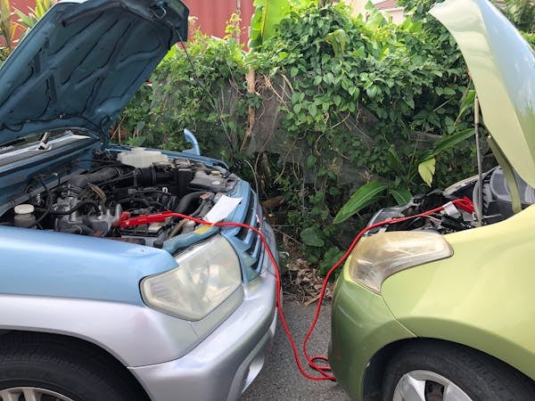A blue and yellow car jumping batteries