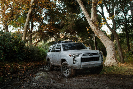 Silver Toyota SUV driving in muddy forest