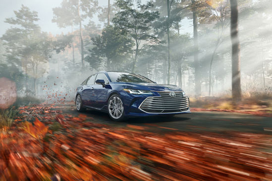 Blue Toyota model driving down a road in autumn