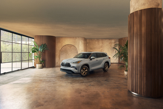 A silver SUV parked in a stylish, modern room with large windows, brown columns, and potted plants. The setting is spacious and sophisticated.