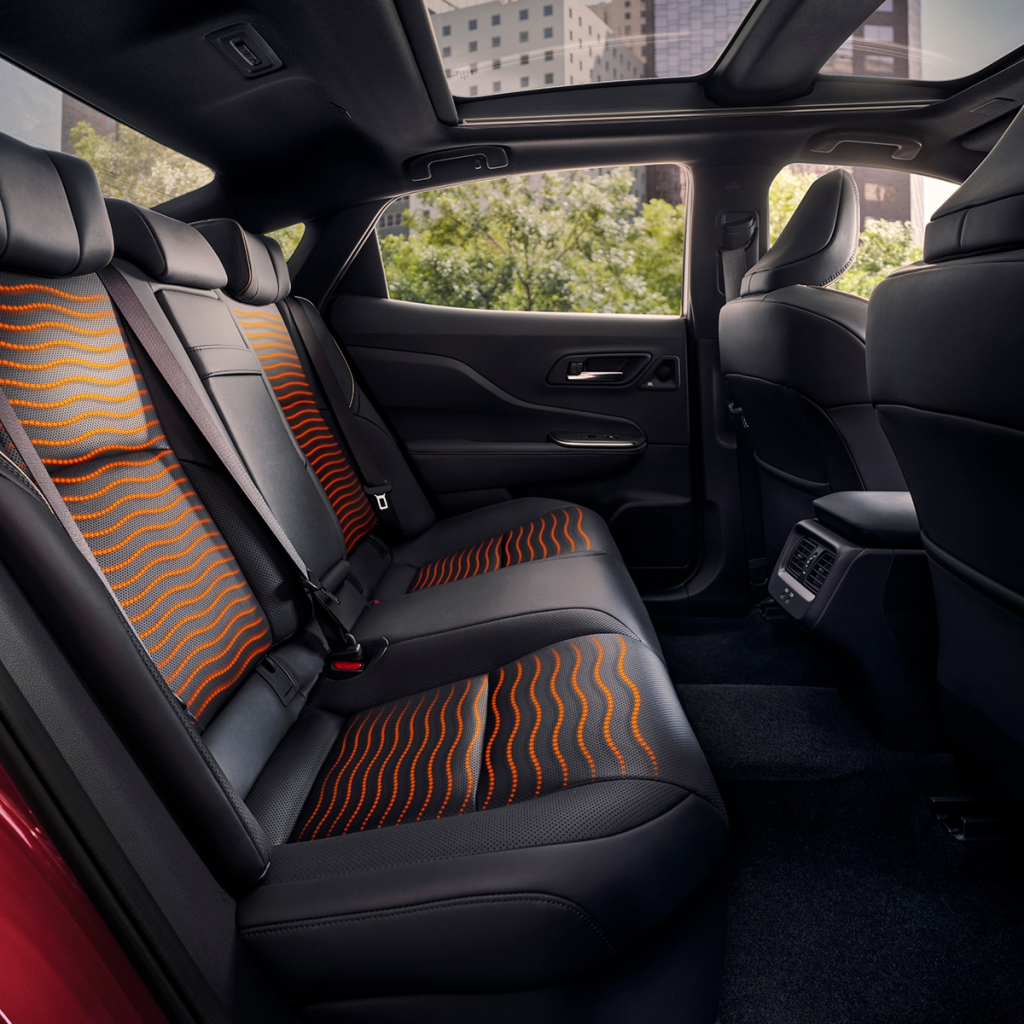 Spacious car interior featuring black leather seats with orange wave patterns, sunroof, and cityscape views through windows, conveying modern elegance.