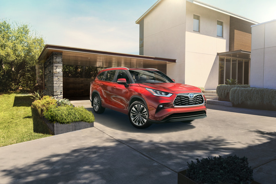 A red SUV is parked on the driveway of a modern house with minimalist architecture. The setting is bright and sunny, conveying a serene suburban atmosphere.