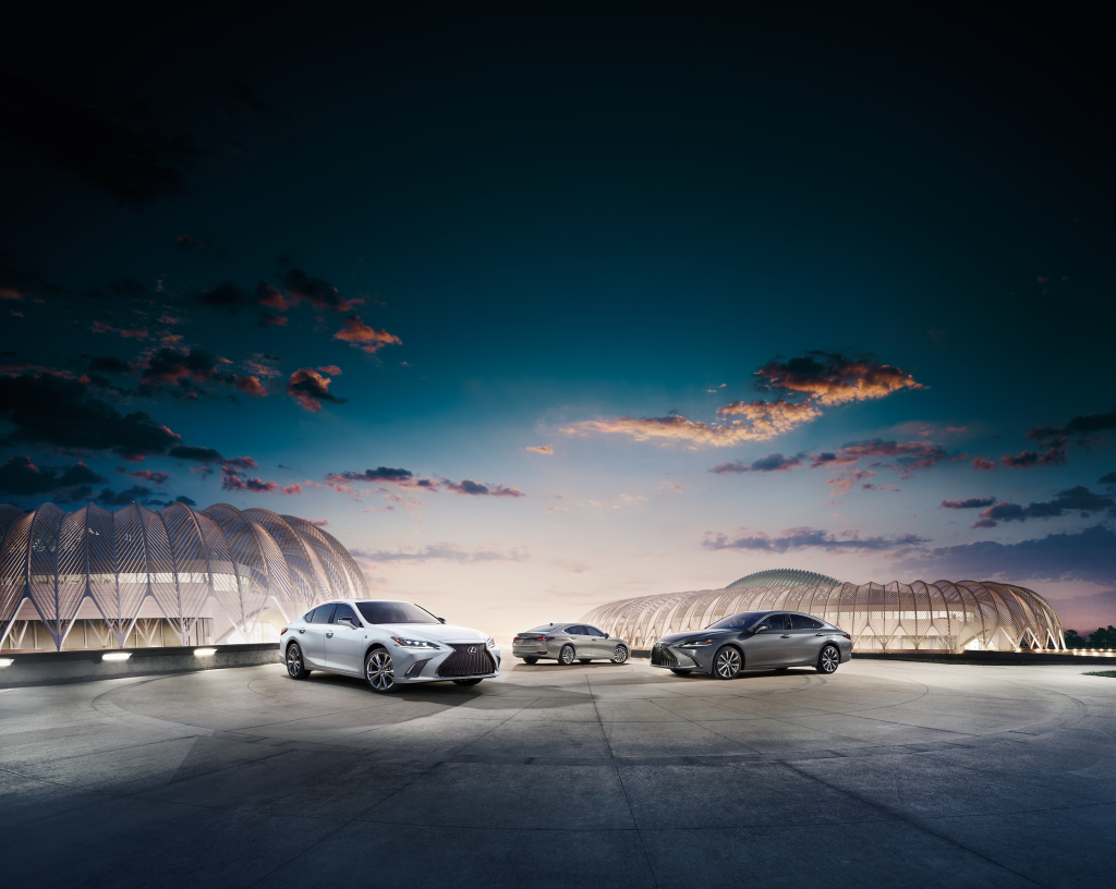 Three luxury cars parked on a modern rooftop with curved architecture, against a dramatic twilight sky with scattered clouds. The scene is sleek and futuristic.